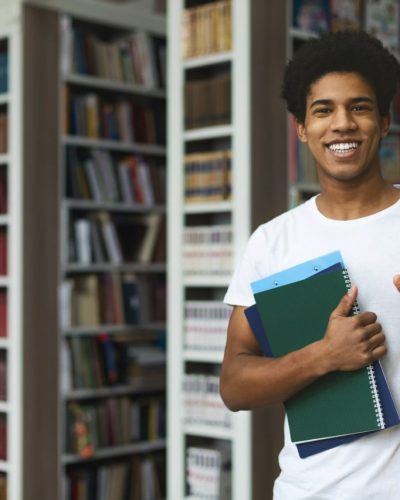 handsome-afro-student-posing-on-bookshelves-background.jpg